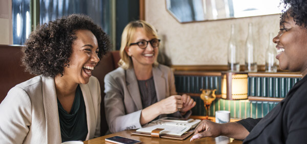 3 women around a table laughing